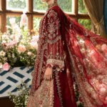 An opulent maroon designer dress with handcrafted embroidery, paired with a richly decorated dupatta, exuding royal elegance.