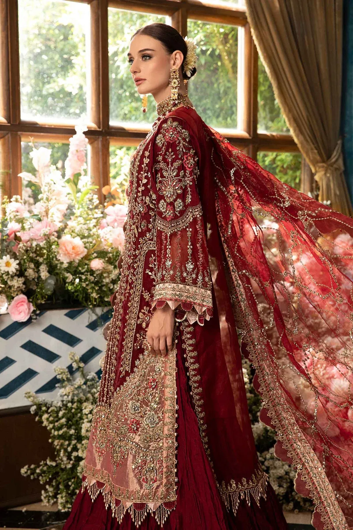 An opulent maroon designer dress with handcrafted embroidery, paired with a richly decorated dupatta, exuding royal elegance.