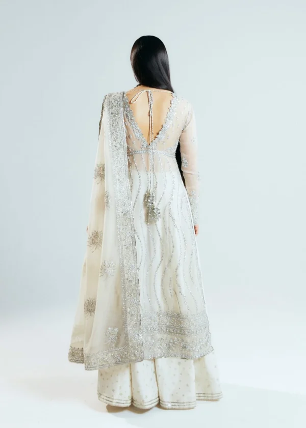 A regal off-white couture ensemble adorned with delicate beadwork, metallic embroidery, and an emerald statement necklace.