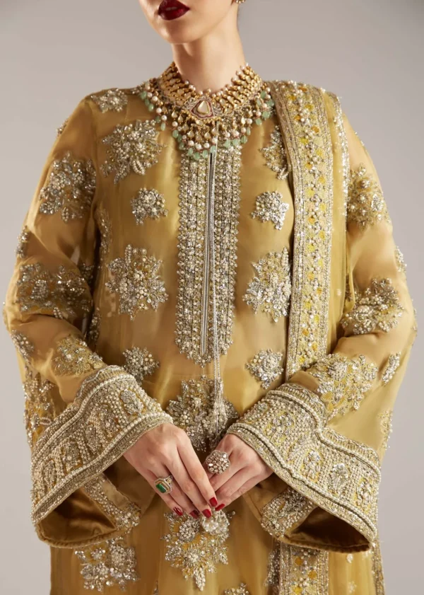 Close-up of a gold bridal outfit with intricate hand embroidery and embellishments.