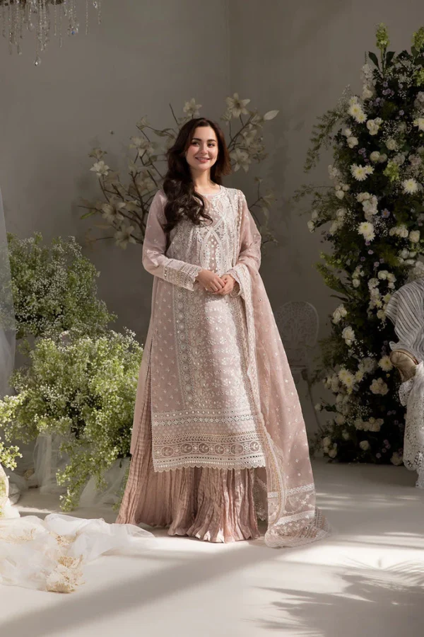 Woman in a soft pink embroidered lawn dress sitting among flowers