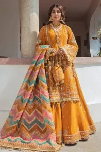 A woman in a vibrant, embellished mustard-yellow Pakistani lehenga with a colorful chevron dupatta and a matching pouch. The image highlights the intricate details and bright aesthetic of the mehndi dresses for girls.