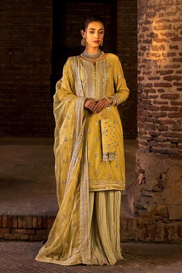 Woman wearing golden embroidered festive outfit with dupatta.