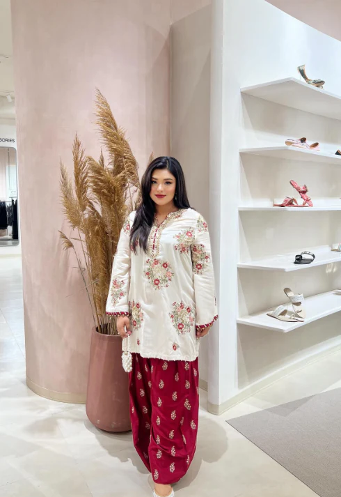 Traditional embroidered ivory outfit paired with maroon trousers.