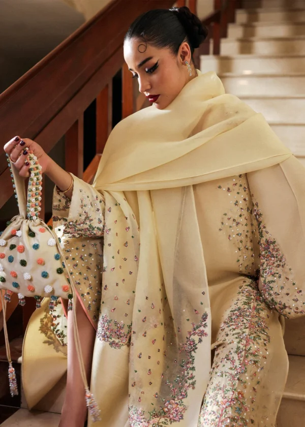 Woman wearing luxury embellished dress with dupatta on staircase.