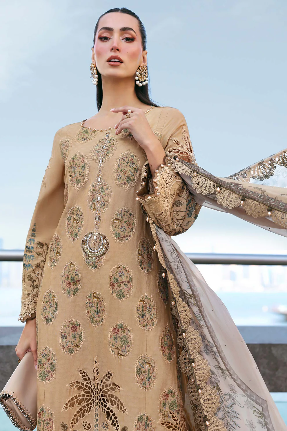 Luxury camel lawn suit with palm tree cutwork & beige chiffon printed dupatta Women wearing embroidered camel lawn suit with beige chiffon dupatta and pearl drops